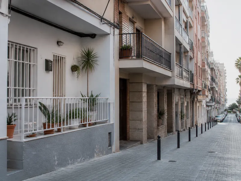 Calle de pisos en Badalona con porches y luz de costa, sin escaparates comerciales